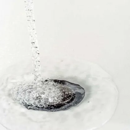 Water is running down a drain in a bathroom sink.
